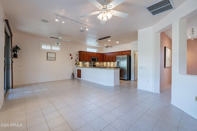 kitchen featuring light tile patterned floors, kitchen peninsula, ceiling fan, stainless steel appliances, and backsplash