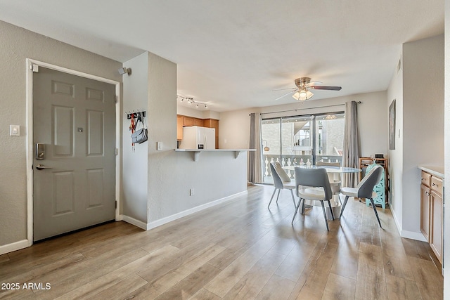 dining space with light wood-type flooring, baseboards, ceiling fan, and rail lighting