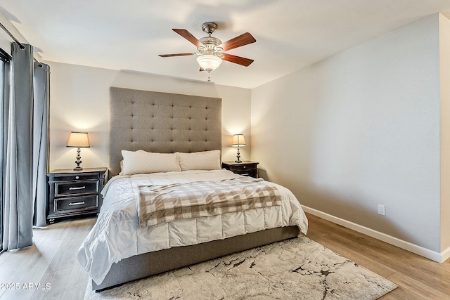 bedroom featuring a ceiling fan, light wood-style floors, and baseboards