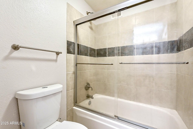 full bathroom with enclosed tub / shower combo, toilet, and a textured wall