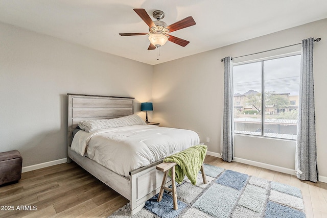 bedroom featuring baseboards, light wood-style floors, and ceiling fan