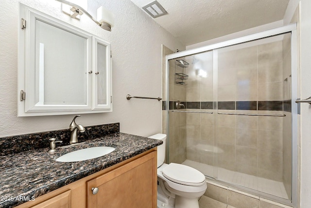 bathroom with toilet, a stall shower, a textured ceiling, vanity, and a textured wall