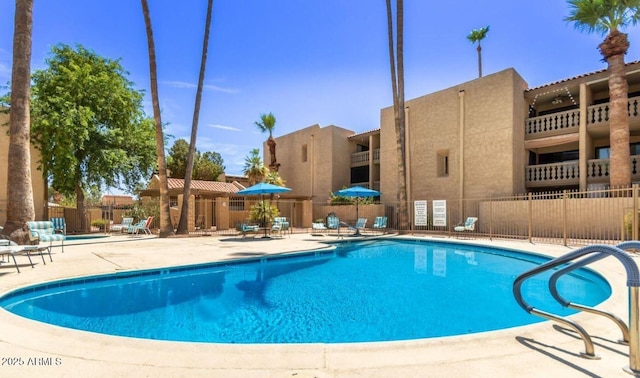 community pool with a patio and fence