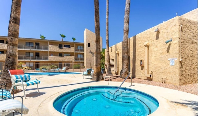 view of swimming pool featuring a patio area, a community hot tub, and fence