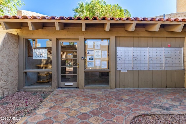 view of exterior entry with a tile roof and stucco siding