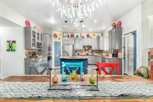 kitchen with decorative backsplash, gray cabinetry, sink, a center island, and appliances with stainless steel finishes