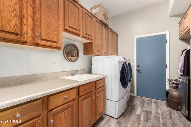 clothes washing area with cabinets, hardwood / wood-style floors, sink, and washing machine and dryer