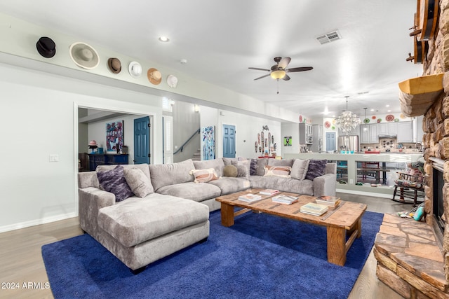 living room with wood-type flooring and ceiling fan with notable chandelier