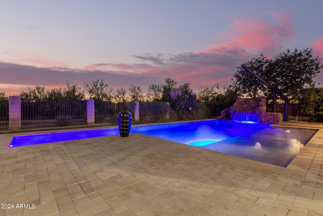 pool at dusk featuring a patio area and pool water feature