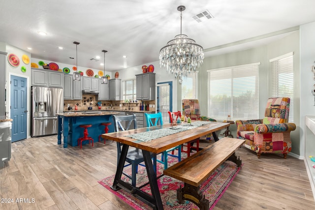 dining area with light hardwood / wood-style flooring and a notable chandelier