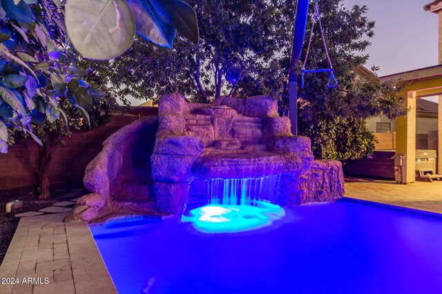 pool at dusk with a patio area and a jacuzzi