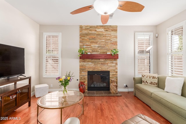 living room featuring a large fireplace, ceiling fan, and light hardwood / wood-style flooring