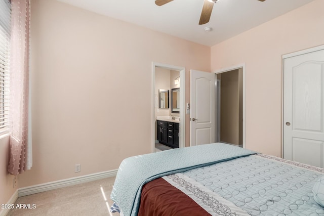 bedroom featuring sink, light carpet, ceiling fan, and ensuite bath