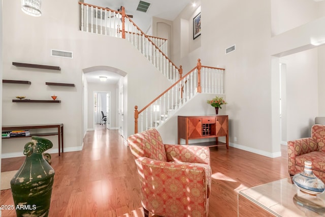 living room with hardwood / wood-style flooring and a towering ceiling