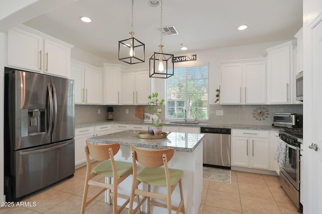 kitchen featuring light tile patterned floors, visible vents, a sink, stainless steel appliances, and white cabinetry