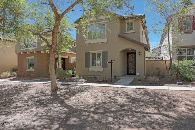 view of front facade with fence and stucco siding