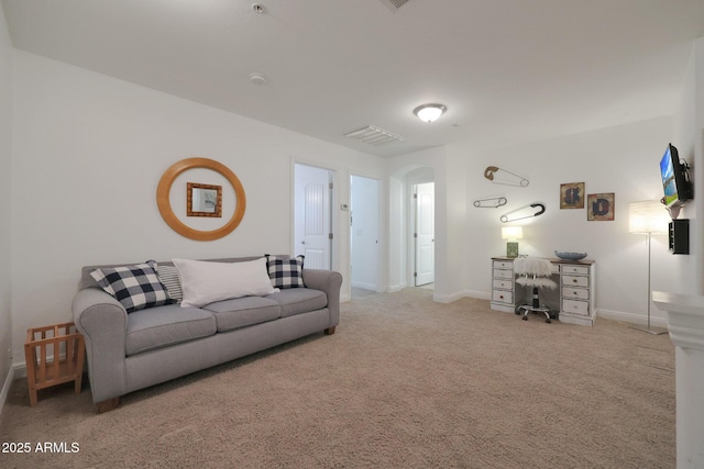 carpeted living room with baseboards and arched walkways