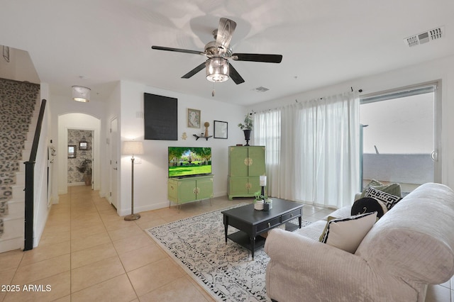 living room featuring light tile patterned floors, visible vents, arched walkways, and ceiling fan