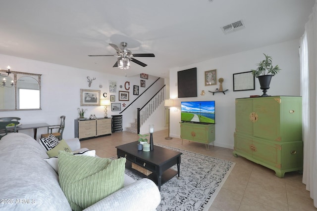 living area featuring light tile patterned floors, visible vents, ceiling fan with notable chandelier, and stairs