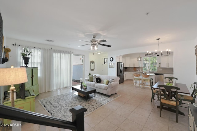 living area featuring light tile patterned flooring, ceiling fan with notable chandelier, visible vents, and arched walkways