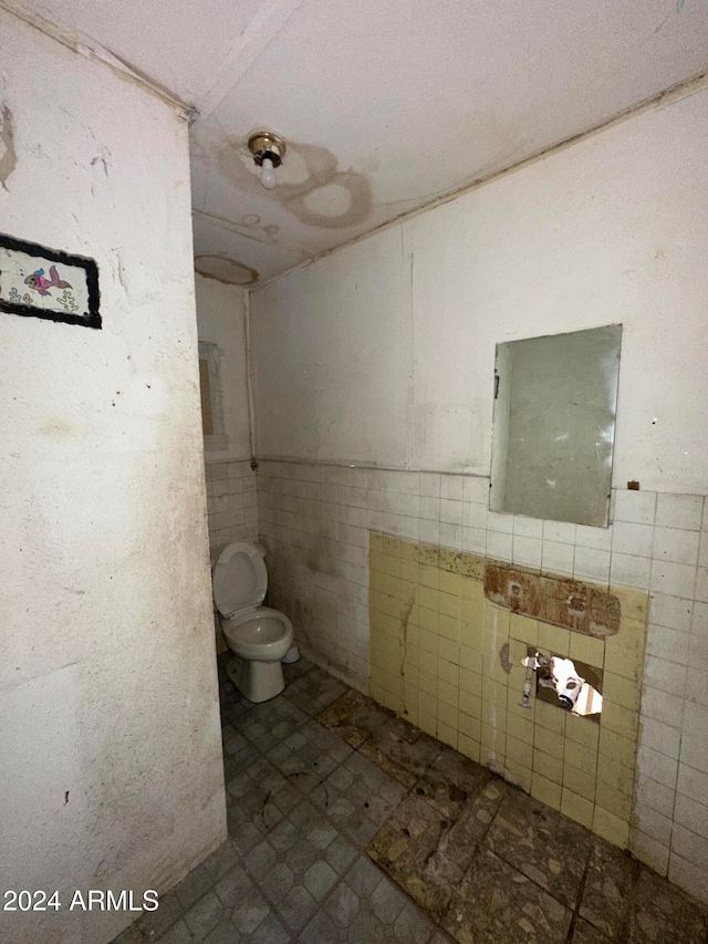 bathroom featuring toilet and tile walls