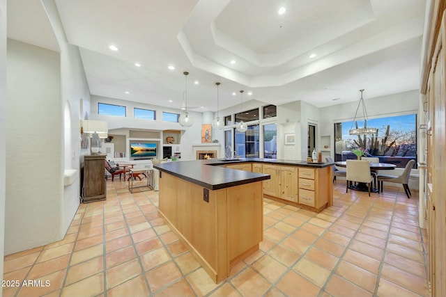 kitchen featuring sink, hanging light fixtures, light brown cabinets, a raised ceiling, and a large island