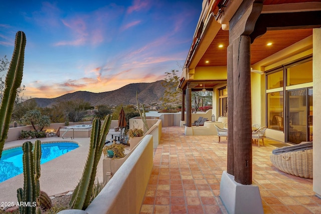 pool at dusk with a mountain view and a patio area