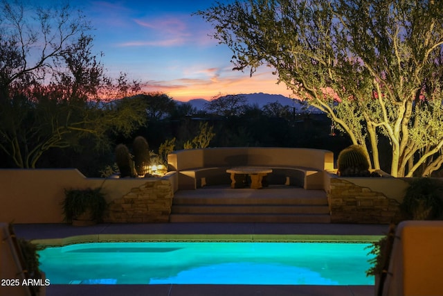 pool at dusk with a mountain view and a patio