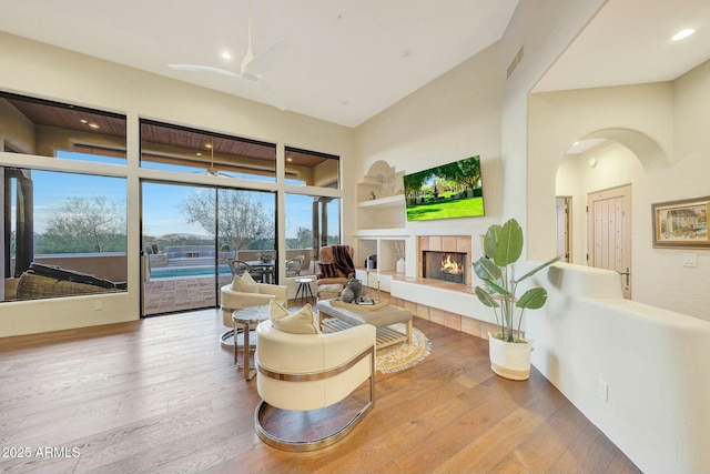 living room with ceiling fan, hardwood / wood-style floors, a fireplace, and built in shelves