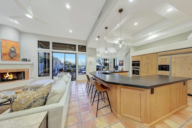 kitchen featuring a spacious island, sink, light tile patterned floors, pendant lighting, and a tiled fireplace