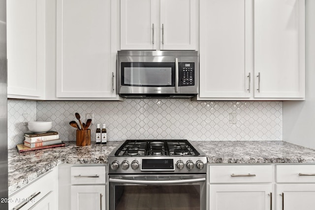 kitchen featuring white cabinetry, backsplash, light stone counters, and appliances with stainless steel finishes