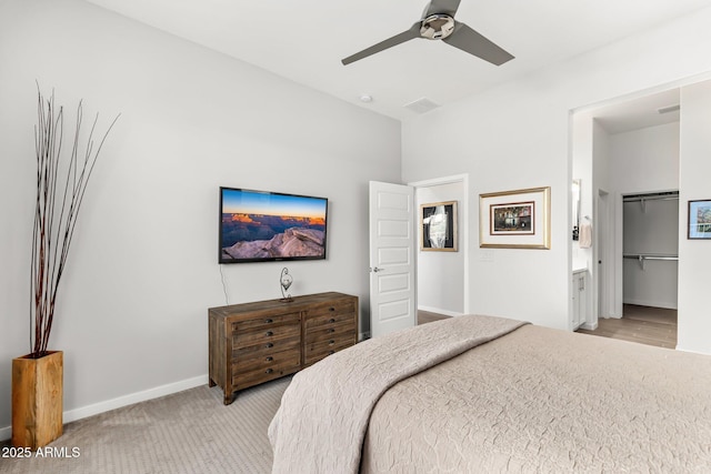 bedroom with ensuite bath, ceiling fan, a walk in closet, light colored carpet, and a closet