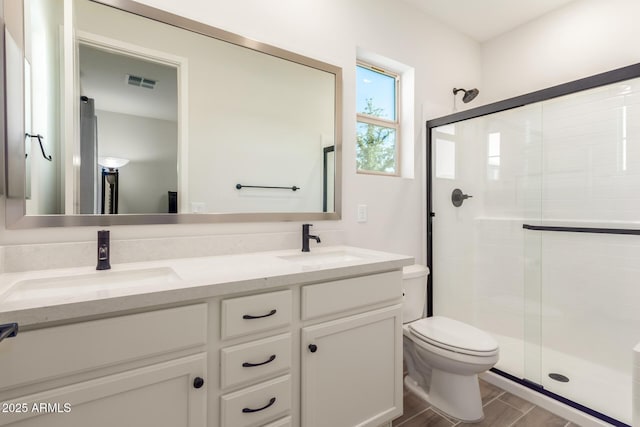 bathroom with vanity, a shower with door, and toilet