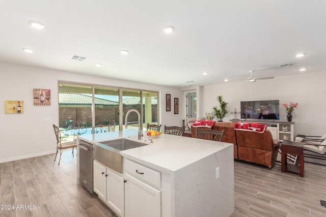 kitchen with white cabinetry, sink, a kitchen island with sink, stainless steel dishwasher, and light hardwood / wood-style floors