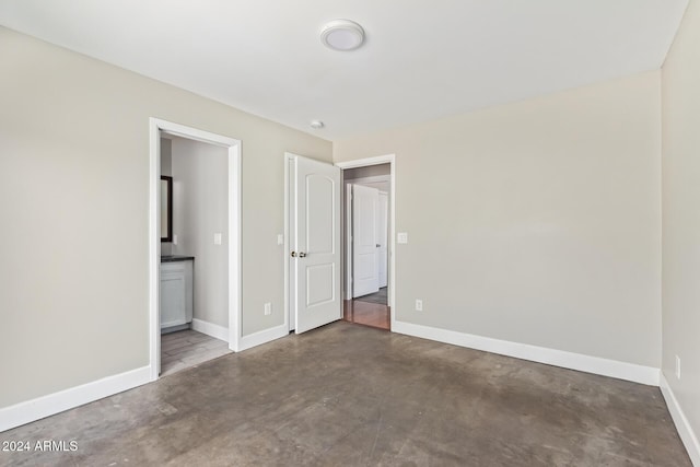 unfurnished bedroom with connected bathroom and concrete floors