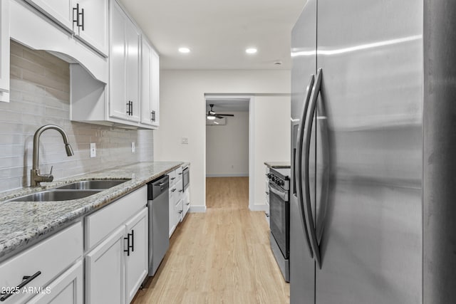 kitchen with light wood finished floors, white cabinets, stainless steel appliances, a ceiling fan, and a sink