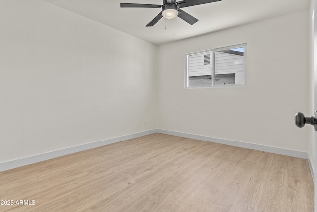 spare room with a ceiling fan, light wood-type flooring, and baseboards