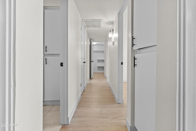 corridor featuring light wood-style flooring, baseboards, and visible vents