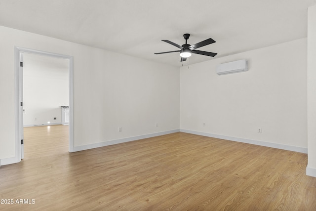 spare room featuring a ceiling fan, light wood-type flooring, a wall mounted air conditioner, and baseboards