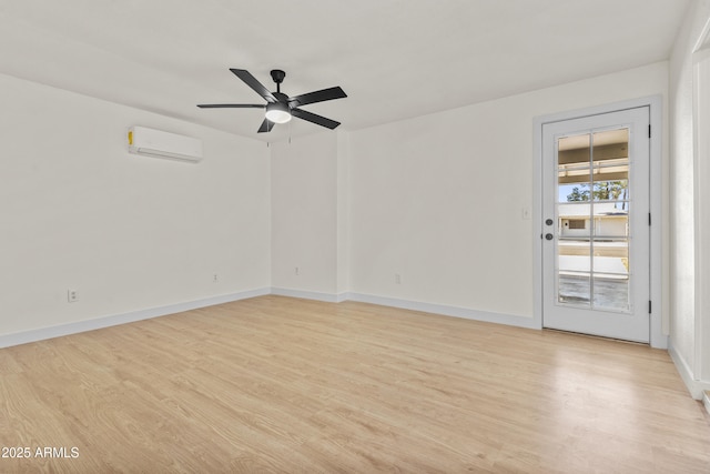 spare room with light wood-type flooring, baseboards, an AC wall unit, and a ceiling fan