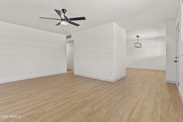 empty room with visible vents, baseboards, light wood-style flooring, and ceiling fan with notable chandelier