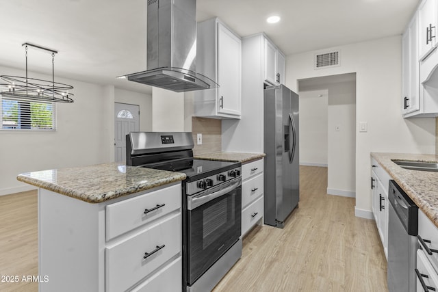 kitchen with visible vents, light wood finished floors, appliances with stainless steel finishes, white cabinetry, and wall chimney range hood