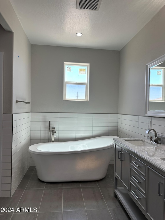 bathroom featuring a wealth of natural light, a bathtub, tile walls, and tile patterned flooring