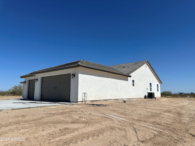 view of property exterior with central air condition unit and a garage