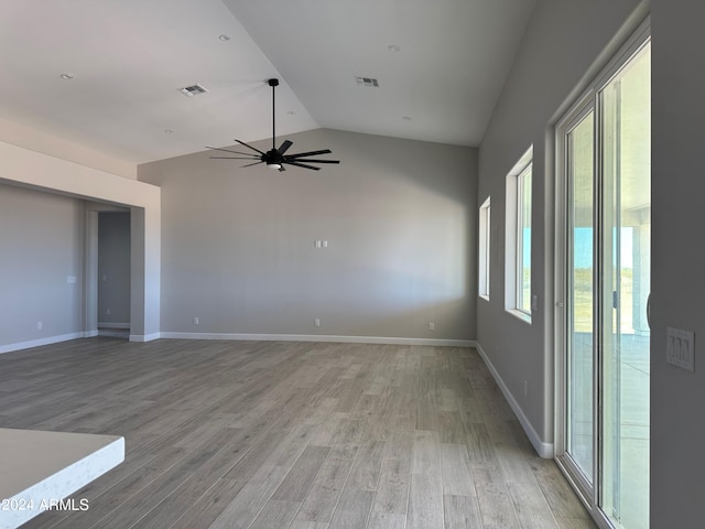 unfurnished room with ceiling fan, light hardwood / wood-style floors, a wealth of natural light, and vaulted ceiling