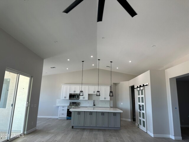 kitchen featuring gray cabinetry, white cabinetry, stainless steel appliances, a barn door, and a kitchen island