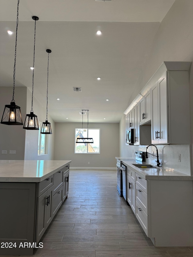 kitchen featuring decorative backsplash, stainless steel appliances, sink, pendant lighting, and wood-type flooring