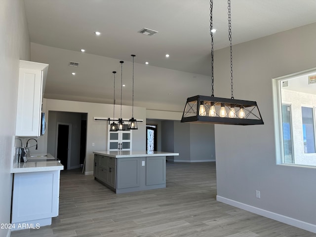 kitchen with sink, hanging light fixtures, a kitchen island, gray cabinets, and white cabinets