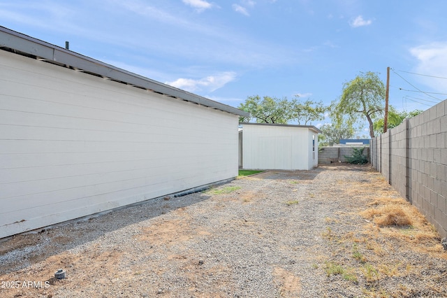 view of yard with an outdoor structure, fence, and a storage shed
