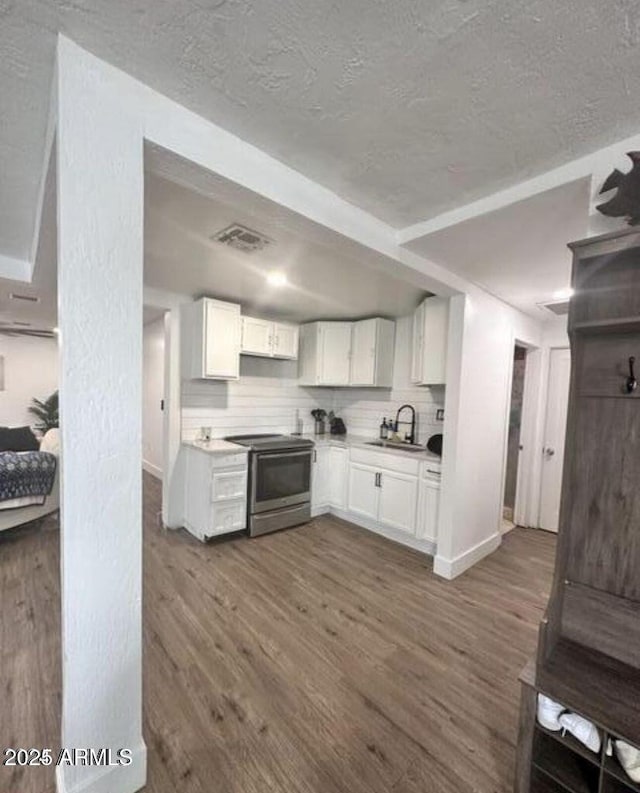 kitchen with a sink, electric stove, visible vents, white cabinets, and dark wood-type flooring